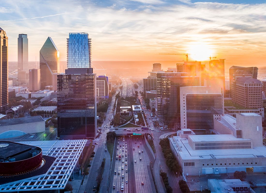 Dallas, TX - Aerial View of a Busy Highway in Downtown Dallas Texas Surrounded by Modern Skyscrapers at Sunset with a Foggy Sky