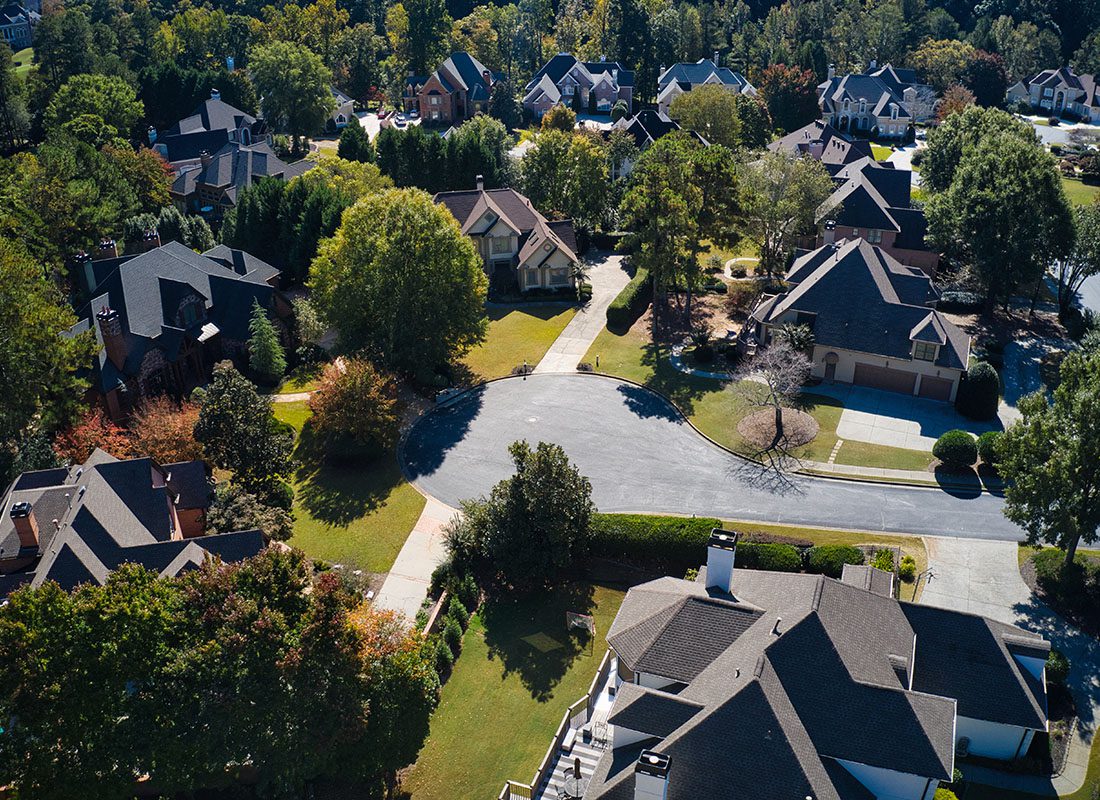Insurance Solutions - Aerial View of Luxury Multi Story Homes Surrounded by Green Trees with Green Font Lawns in the Suburbs