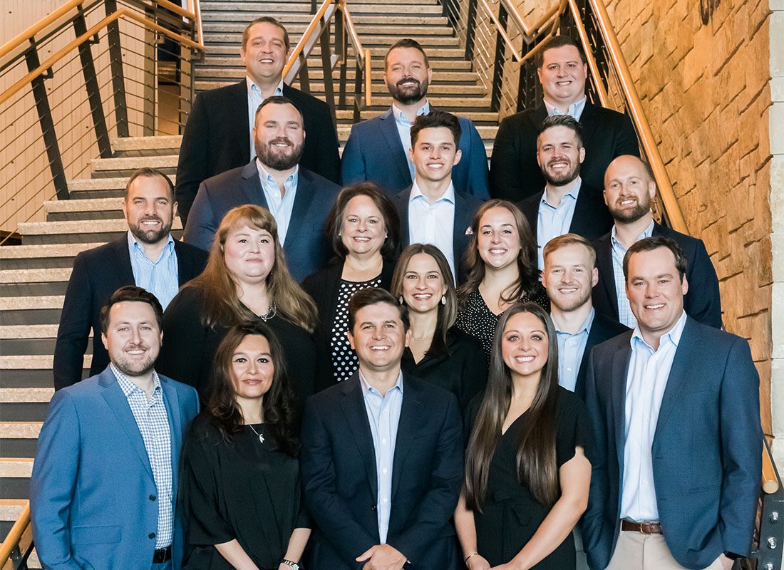 About Our Agency - Team Photo of the C1 Insurance Group Staff Dressed in Business Attire Standing in Front of a Long Staircase at an Event